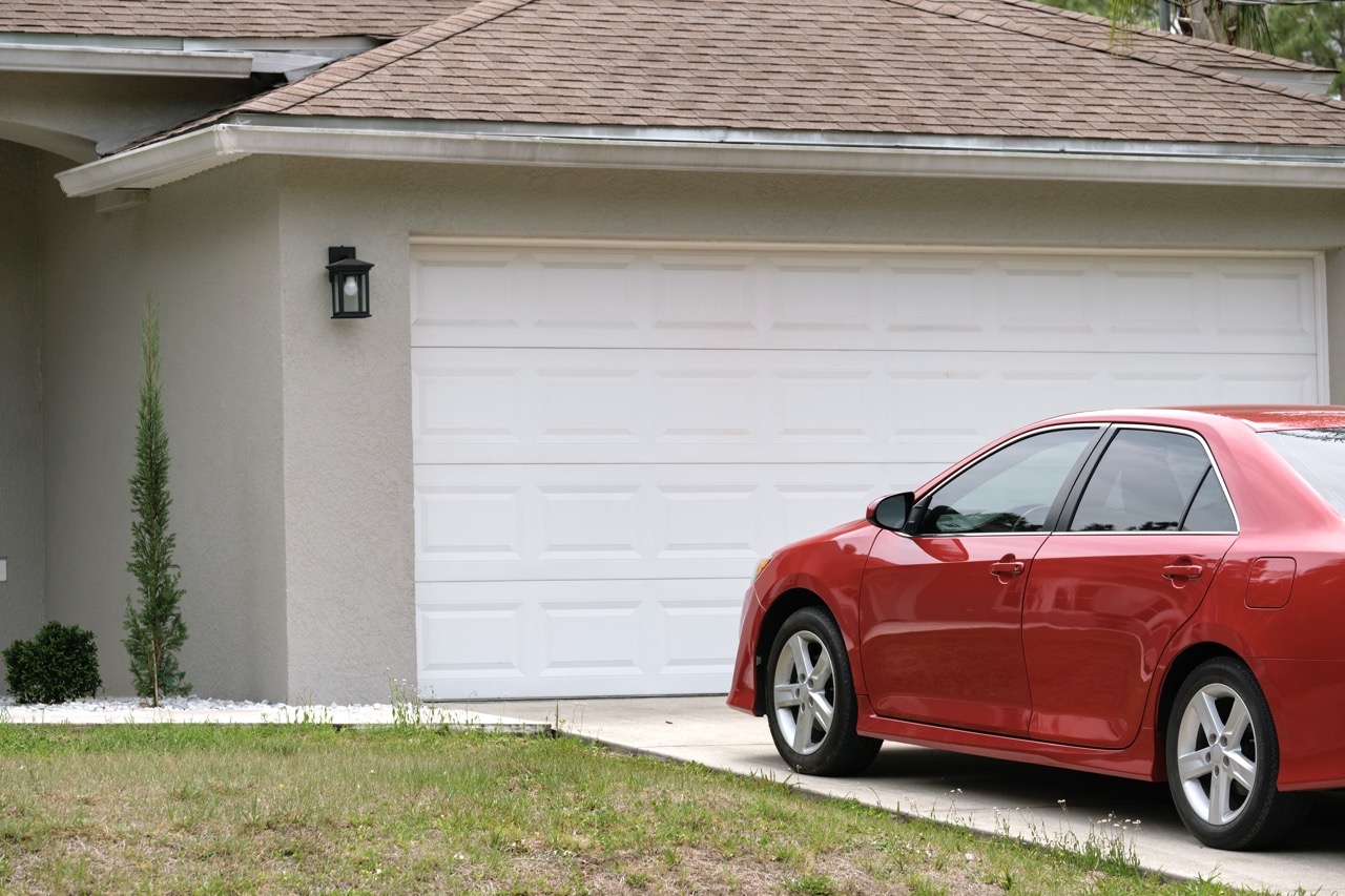 Car parked in front of wide garage double door on concrete driveway of new modern american house Car parked in front of wide garage double door on concrete driveway of new modern american house.